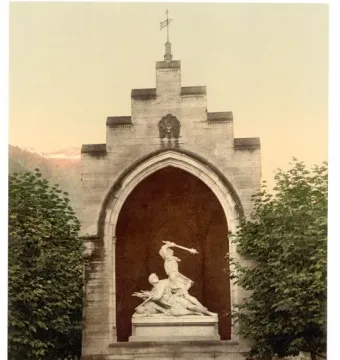 Winkelried Memorial with a stone arch niche framing a white marble sculpture of two figures, set among trees with mountains in the background.