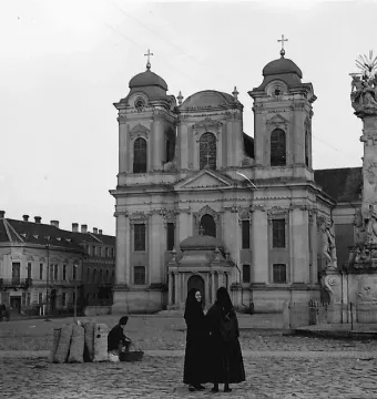 Holy Trinity Monument standing in a cobbled town square with a church in the background.