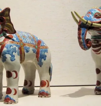 Pair of Kakiemon porcelain elephant figurines decorated in white, blue, red, and gold with yellow tusks.