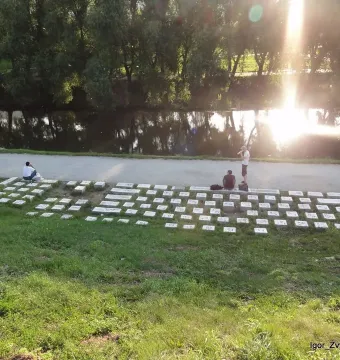 Keyboard Monument made of stone blocks along a grassy riverbank with people among the keys