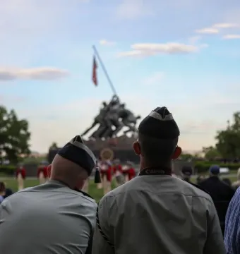 Marine Corps War Memorial with spectators seated in the foreground and the bronze flag-raising sculpture in the background.