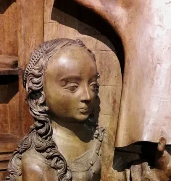 Wooden bust of Saint Luke with long curly hair and hands held out in front.