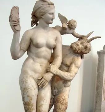 Aphrodite, Pan and Eros sculpture showing a nude woman holding a sandal above her head as Pan grasps her arm and a winged child presses down on Pan.