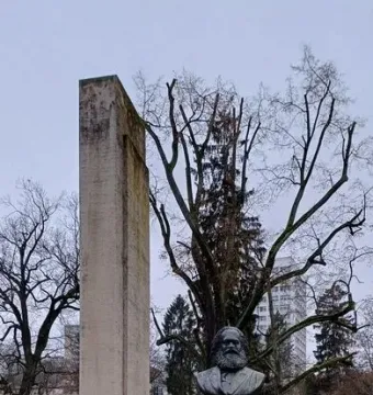 Karl Marx Monument with a dark bust on a pedestal in front of a tall concrete stele.