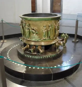 Baptismal font at St Bartholomew\'s Church with bronze relief figures and animal supports.