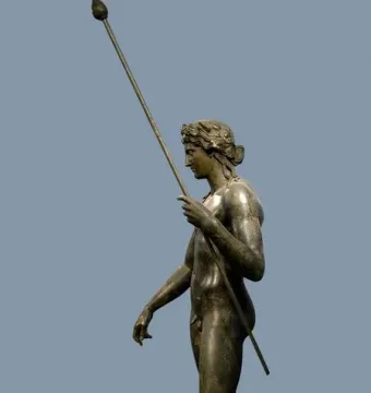 Bronze statue of Dionysus standing in profile on a circular base with a spear and wreath