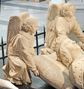 Detail of the Tomb of Francis II showing a recumbent figure’s head resting on a patterned pillow, with kneeling angels supporting it.