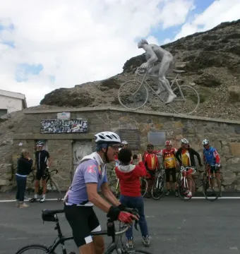 Géant du Tourmalet statue of a nude male cyclist pedaling on a bicycle, with real cyclists gathered around the base.