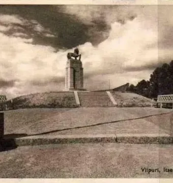 Lion statue atop a tall stepped monument in Monrepos, with spherical sculptures in the foreground.
