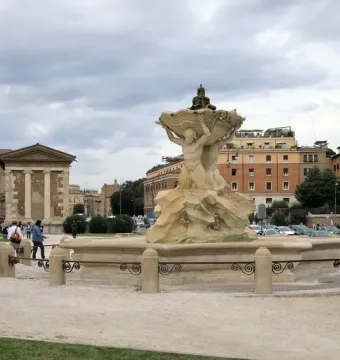 Fountain of the Tritons with two sculpted figures holding a large shell in a paved square.