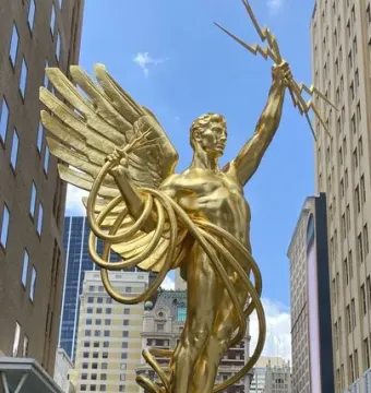 Golden Boy statue of a winged male figure holding lightning bolts and a coiled cable in Dallas.