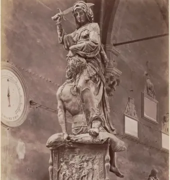 Donatello\'s Judith and Holofernes bronze sculpture, showing a robed woman holding a raised sword over a kneeling man she grips by the head.