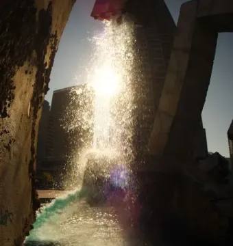 Vaillancourt Fountain with water splashing brightly in the sun between dark concrete structures.