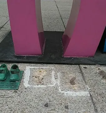 Antimonumento 49 ABC with small sculptural shoes placed on the pavement beside faded painted square outlines.