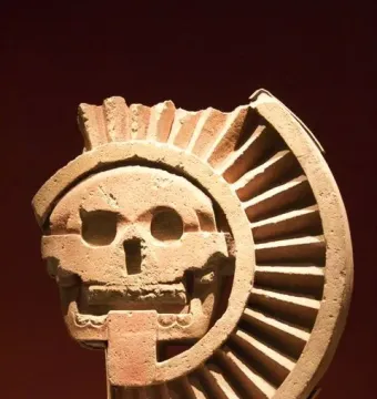 Disk of Mictlāntēcutli stone carving with a skull-like face and ribbed fan-shaped detail
