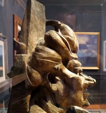 L\'antigrazioso, a bronze-toned abstract fragmented head in profile with angular and swirling forms.