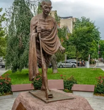 Mahatma Gandhi Memorial bronze sculpture of Gandhi walking with a staff on a stone pedestal.
