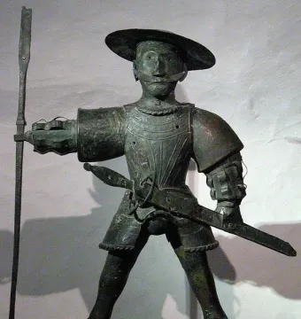 Old Thomas statue of a man in armor with a wide-brimmed hat, mustache, spear, and sword