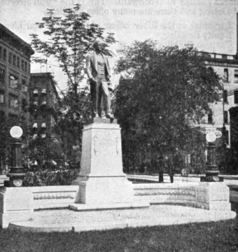 The Stevens T. Mason Monument rises on a multi-tiered stone pedestal, with low stone walls and small globes at each end.