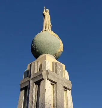 Divino Salvador del Mundo statue of Jesus standing on a globe against a blue sky