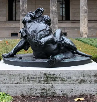 Bronze sculpture of Hercules wrestling the Nemean Lion on a stone pedestal.