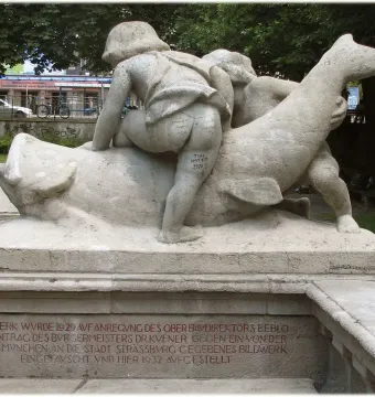 Rhine Water Fountain sculpture with two youthful figures and a large fish-like creature, with red inscription on the base.
