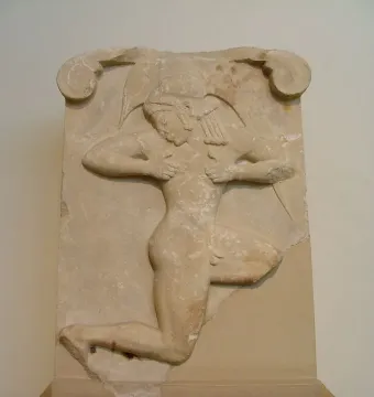 Runner Relief showing a carved figure in high relief on a weathered stone panel, posed in a crouching posture with bent arms.