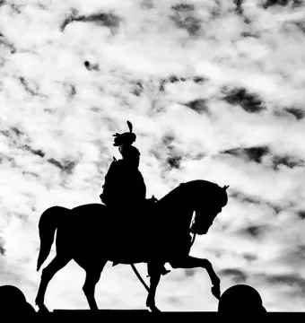 Silhouetted rider on the Victor Emmanuel II Equestrian Statue against a cloudy sky.