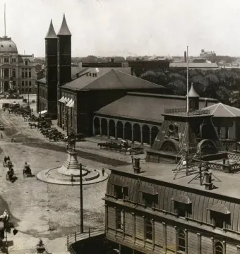 Ambrose Burnside Monument in a historic city square with horse-drawn carriages and brick buildings nearby.