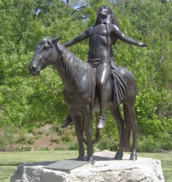 The Appeal to the Great Spirit sculpture shows a bare-chested man with long hair riding a horse, arms spread wide and head tilted back on a stone base.