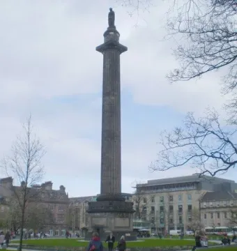The Melville Monument rises from St Andrew\'s Square Gardens beside paved walkways and lawn, with people walking nearby.