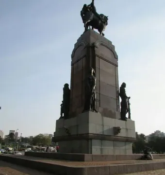 Monument to General Carlos M. de Alvear with a dark equestrian statue atop a tall stone pedestal and standing figures at the base