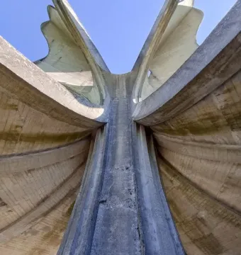 The Stone Flower monument rises in concrete petal-like forms against a clear blue sky.