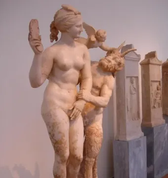 A marble sculpture of Aphrodite with Pan and Eros, showing Aphrodite raising a sandal as Pan grasps her and Eros reaches in from behind.