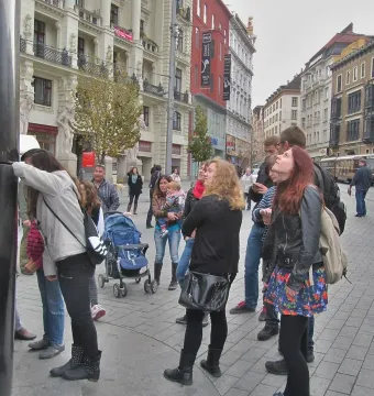 The Brno astronomical clock stands in a busy square with a crowd of people gathered around it.