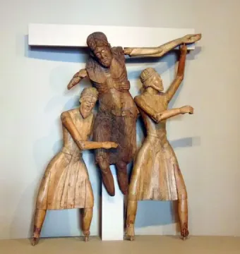 Wooden Descent from the Cross sculpture with a central figure being lowered from a beam by two robed figures, flanked by two crucified figures.