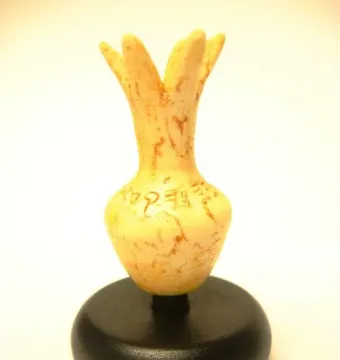 Ivory Pomegranate replica with a narrow neck, petal-like top, and faint ancient inscriptions on a rounded body.