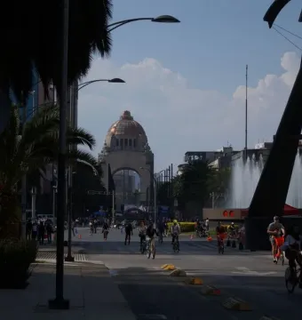 Puerta 1808 stands beside a wide, palm-lined avenue with a domed building in the background.