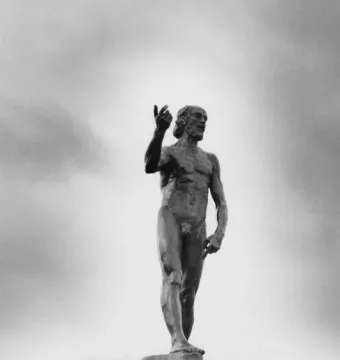 Saint John the Baptist sculpture of a bearded nude man raising one arm and pointing upward.