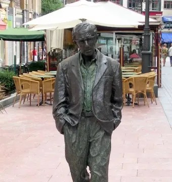 Woody Allen Memorial sculpture of a man in spectacles, jacket, and loose trousers standing with hands in pockets.