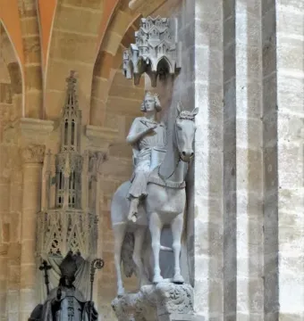 The Bamberg Horseman mounted on a horse and displayed high on a bracket inside a Gothic cathedral interior.