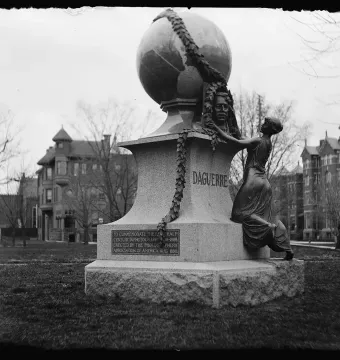 Daguerre Memorial with a globe at the top and a kneeling bronze figure at the base