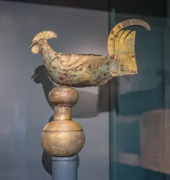 Gallo di Ramperto rooster weather vane sculpture with a gilded surface on a two-tiered pedestal.