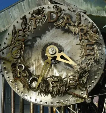 Close-up of the Hornsby Water Clock face with brass hands, bronze letters, and decorative animal figures around the rim.