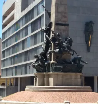 Monumento a Júlio de Castilhos with a tall stone obelisk on a multi-tiered base and bronze figures around it.