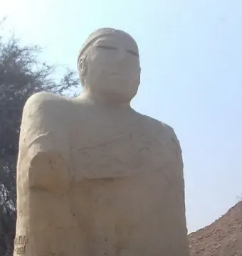 Upper torso of the Priest-King statue showing a bearded man with a forehead band and draped cloak patterns.