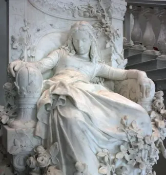 Sleeping Beauty sculpture of a reclining woman in a decorated armchair with roses and foliage