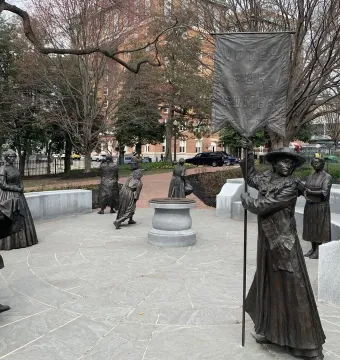 Virginia Women\'s Monument with life-sized metallic statues arranged in a circle, including a central figure holding a Votes for Women banner.