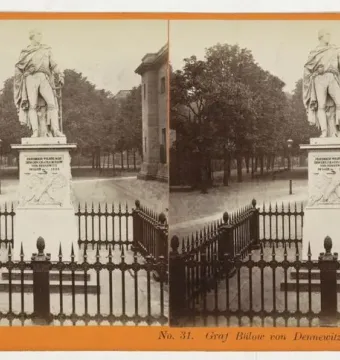 Stereoscopic card showing the Bülow Monument in Berlin, with the statue on a pedestal behind a low fence.