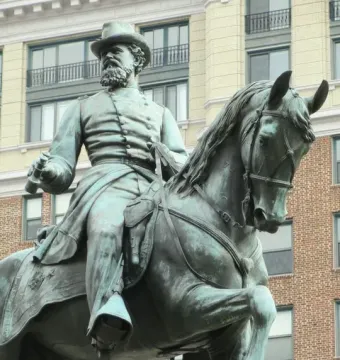 Bronze equestrian statue of General James B. McPherson with a raised horse leg, set against modern buildings.